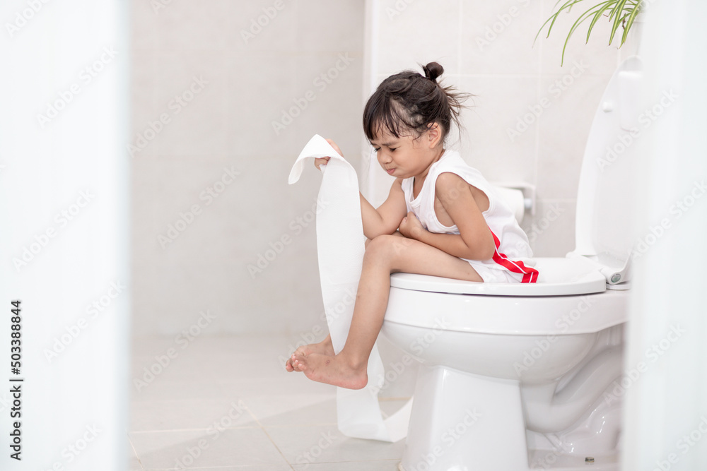 The little girl is sitting on the toilet suffering from constipation or hemorrhoid. StockFoto