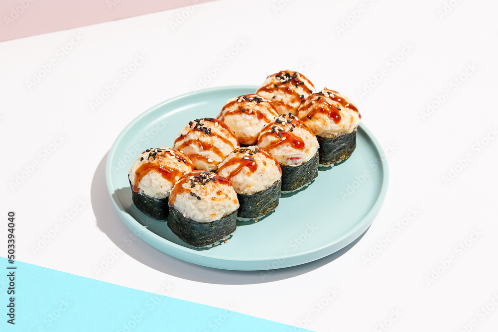 Hot sushi roll with cream cheese top. Baked sushi with seafood and crab, cream cheese topped. Hot maki sushi on coloured background in minimal style. Hot sushi roll with cream cheese top. Baked sushi with seafood and crab, cream cheese topped. Hot maki sushi on coloured background in minimal style.