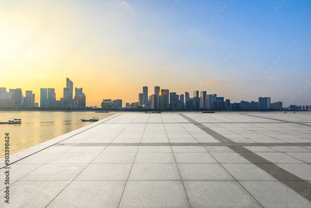 Empty square floor and city skyline with modern commercial buildings in Hangzhou at sunset, China.