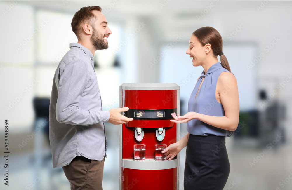 Man and woman talking near water cooler in office - obrazy, fototapety, plakaty 
