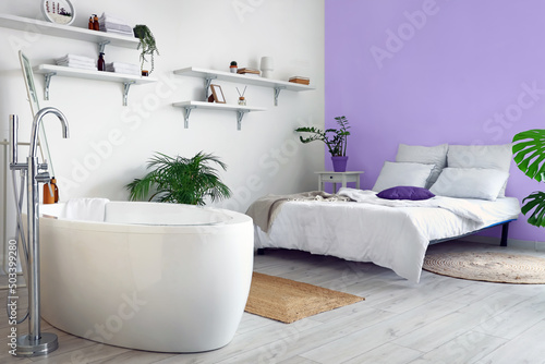 Modern studio apartment with comfortable bathtub and bed
