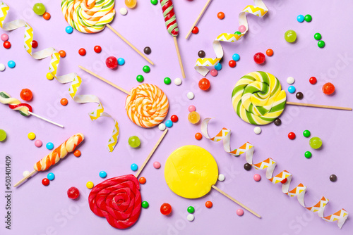 Many different lollipops and candies on lilac background