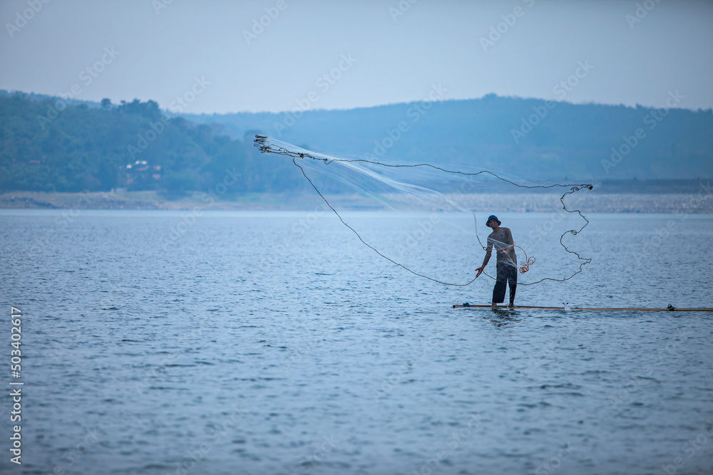 A man crawling fish in Jati Luhur Dam, Purwakarta, West Java, Indonesia. A man crawling fish in Jati Luhur Dam, Purwakarta, West Java, Indonesia.