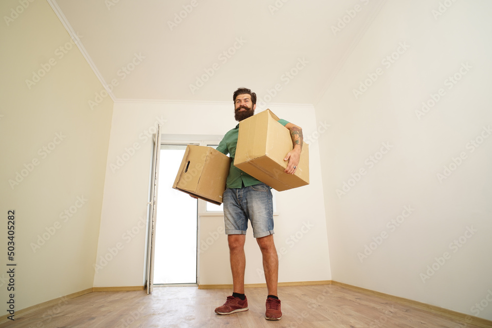 Man carrying cardboard box on moving day. Delivery man loading cardboard boxes for moving to an apartment. Man carrying cardboard box on moving day. Delivery man loading cardboard boxes for moving to an apartment.
