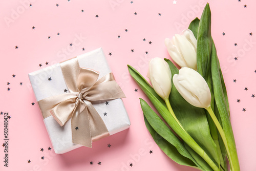 Gift box with tulips and glitters on pink background