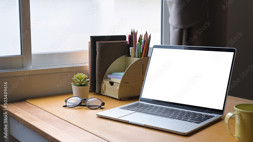 Computer laptop, glasses, coffee cup and supplies on wooden table. Blank screen for graphics display montage. Computer laptop, glasses, coffee cup and supplies on wooden table. Blank screen for graphics display montage.