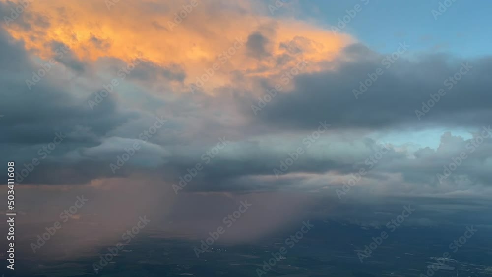 Aeral view from a jet cockpit approaching to Seville airport of a huge cumuloninbus while rainning with orange clouds Aeral view from a jet cockpit approaching to Seville airport of a huge cumuloninbus while rainning with orange clouds