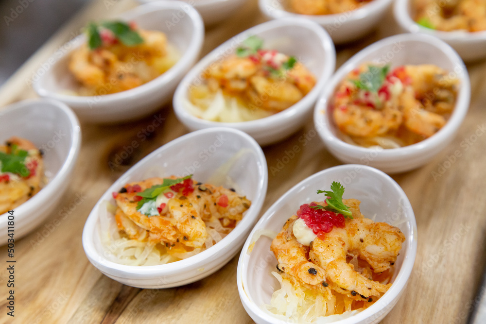 small plates of prawn shrimp fresh cooked with noodles and green herbs low light out of focus with grain