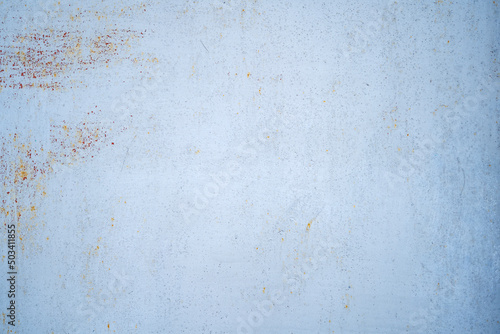 Light blue paint background on metal with a fine element of worn rust. 