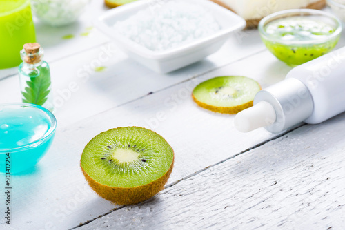beauty products with kiwi fruit ingredient on white wooden table