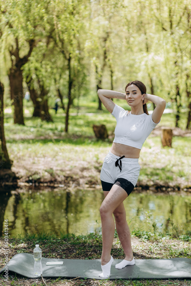 Young athletic woman doing longitudinal splits outdoors. Girl go in for sports, healthy lifestyle, athletic body. She is in sportswear, black top and shorts. Sport concept.