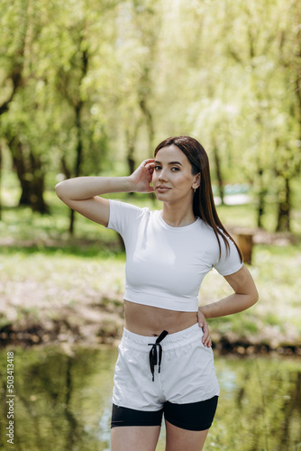 Fototapeta Naklejka Na Ścianę i Meble -  Young athletic woman doing longitudinal splits outdoors. Girl go in for sports, healthy lifestyle, athletic body. She is in sportswear, black top and shorts. Sport concept.