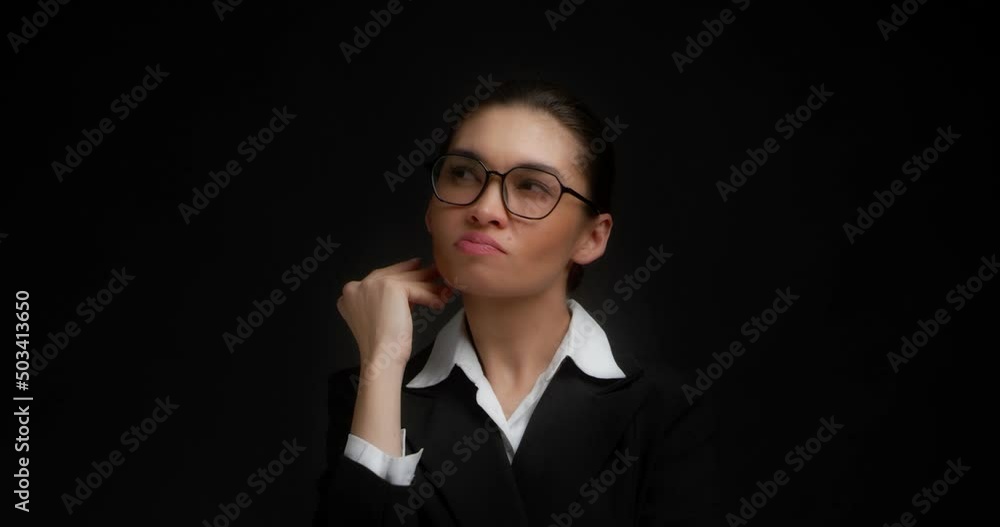 A confused businesswoman in glasses and office clothes scratches her head, holds her chin with her hand, remembers something and thinks about it. Isolated on a black background A confused businesswoman in glasses and office clothes scratches her head, holds her chin with her hand, remembers something and thinks about it. Isolated on a black background