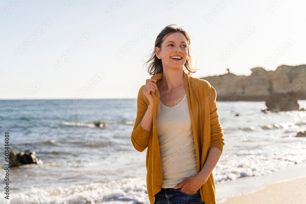 Smiling woman standing at beach on sunny day Smiling woman standing at beach on sunny day
