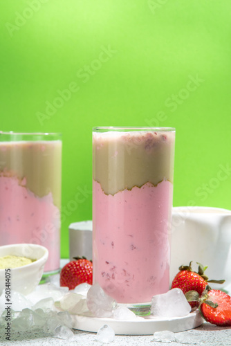Natural healthy summer drink. Diet organic strawberry and matcha latte cocktail, with fresh strawberry and ice, on a white light green background