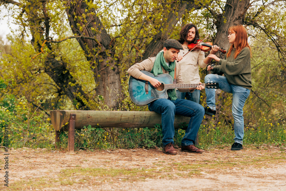 Artists with musical instruments practicing near bench by tree