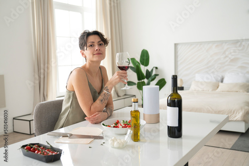 Woman holding wineglass sitting on chair at home