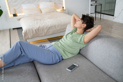 Woman with hands behind head resting on sofa at home photo