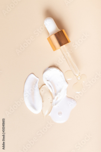 Top drops and smears of cream cosmetics with a pipette on a beige background