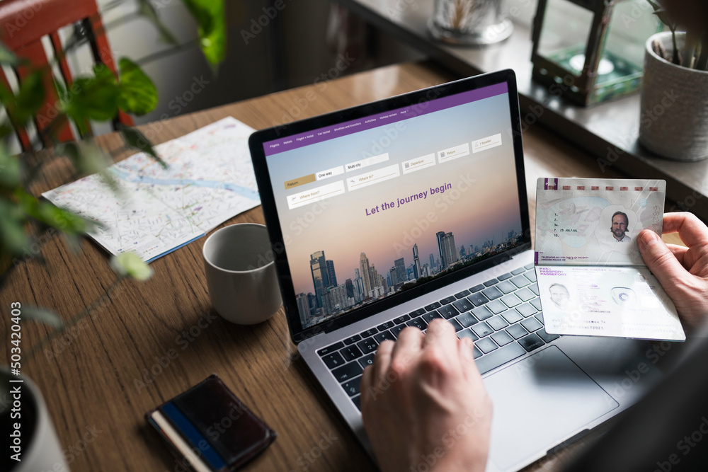 Man searching for flights on laptop and holding passport Man searching for flights on laptop and holding passport