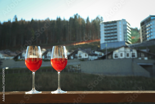 Glasses of wine on wooden balcony in ski resort © Atlas
