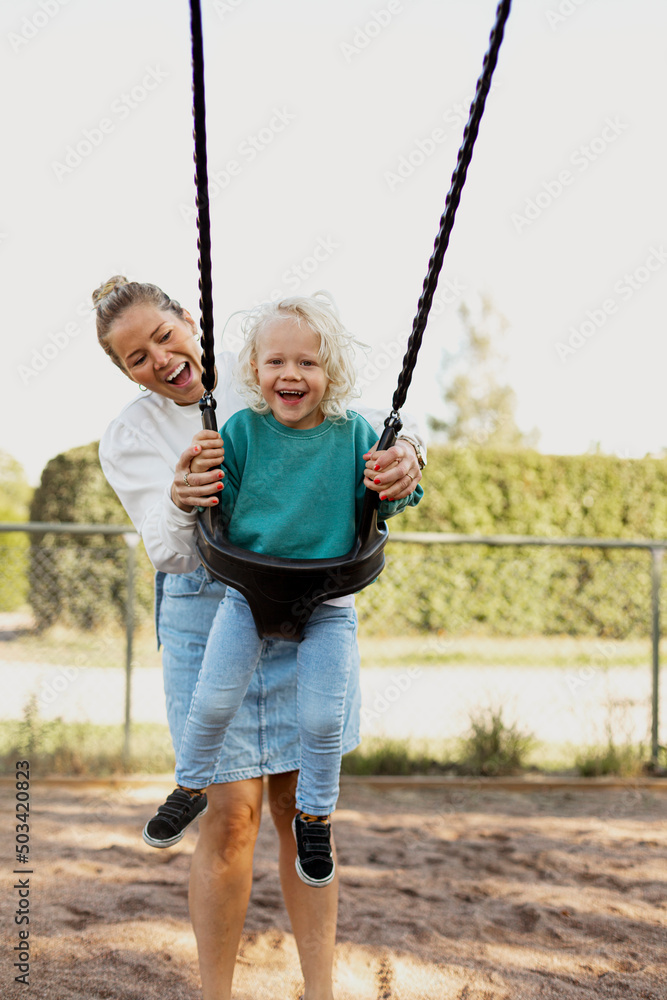 Happy mother swinging child at playground Happy mother swinging child at playground