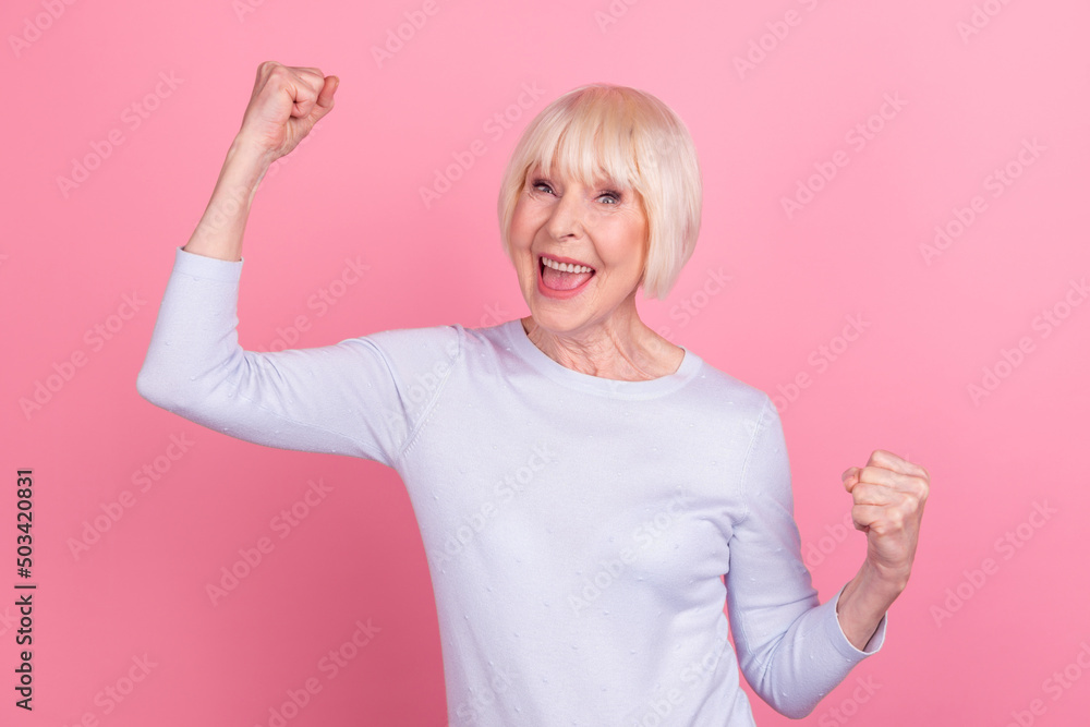Photo of cheerful pretty woman rejoice victory fists hands yes luck fan goal isolated over pink color background Photo of cheerful pretty woman rejoice victory fists hands yes luck fan goal isolated over pink color background