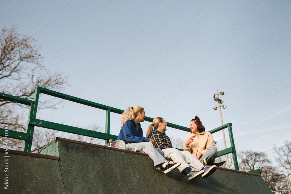 Smiling teenage girls sitting in skatepark Smiling teenage girls sitting in skatepark