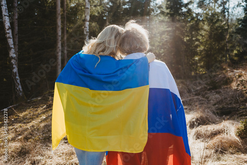 Rear view of women wrapped in Ukrainian and Russian flags photo
