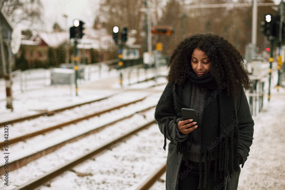 Woman at train station platform using cell phone