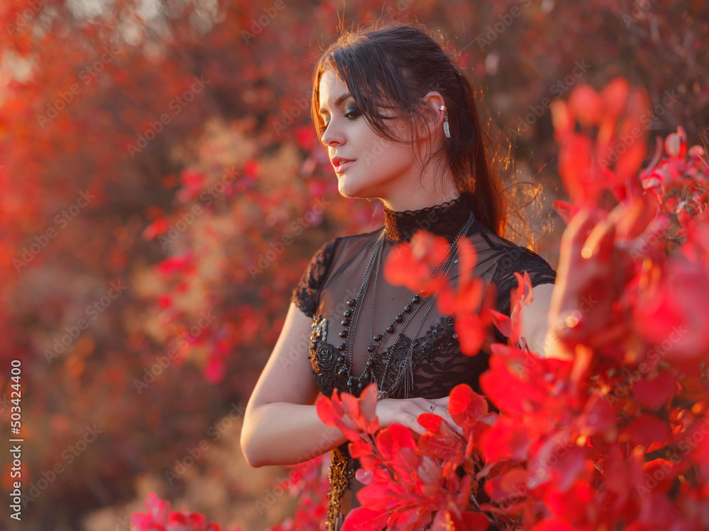 woman in black dress enjoys the sunset in autumn forest