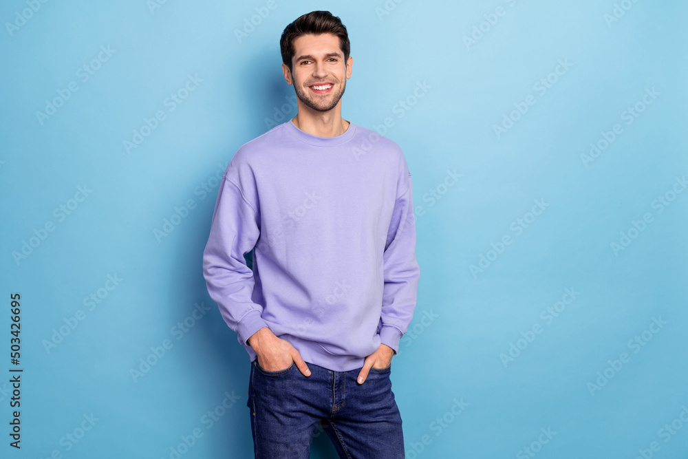Portrait of attractive cheerful content guy holding hands in pockets isolated over bright blue color background Portrait of attractive cheerful content guy holding hands in pockets isolated over bright blue color background