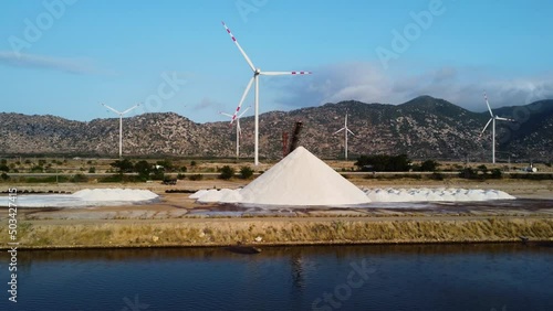 Heap Of Salts At Salt Pan With Wind Turbines In The Distance. - aerial photo