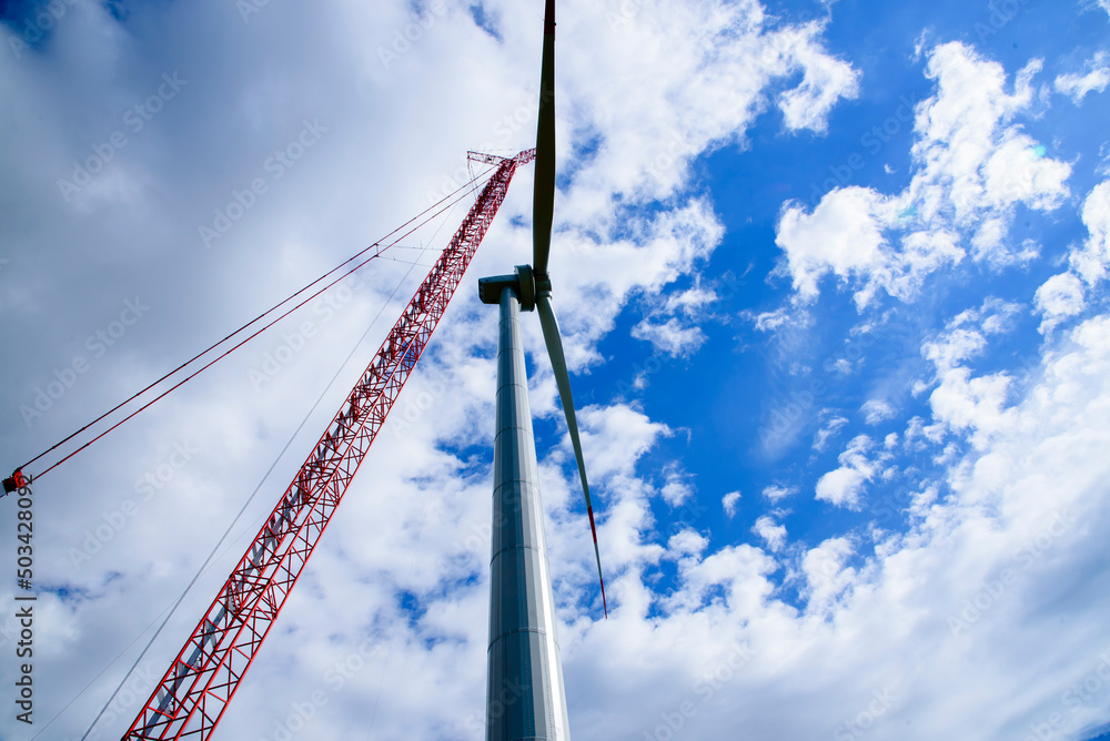 Construction of Wind Turbine Tower using Big red crane under beautiful blue sky. Clean alternative energy concept to reduce global warming and climate change for sustainable growth and developement. Construction of Wind Turbine Tower using Big red crane under beautiful blue sky. Clean alternative energy concept to reduce global warming and climate change for sustainable growth and developement.