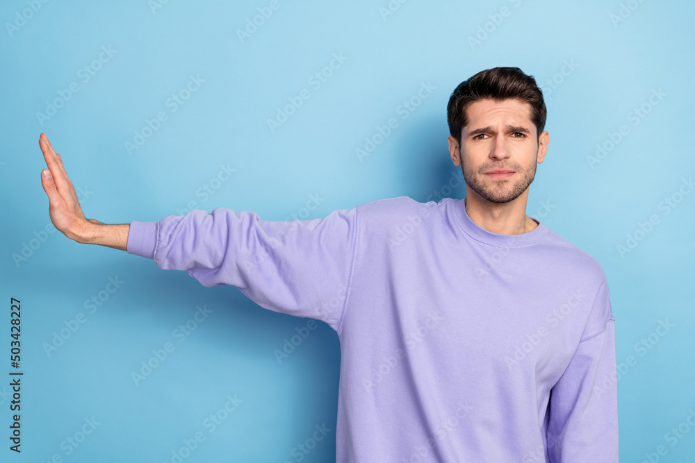 Photo of unhappy millennial brunet guy show no wear sweater isolated on blue color background Photo of unhappy millennial brunet guy show no wear sweater isolated on blue color background