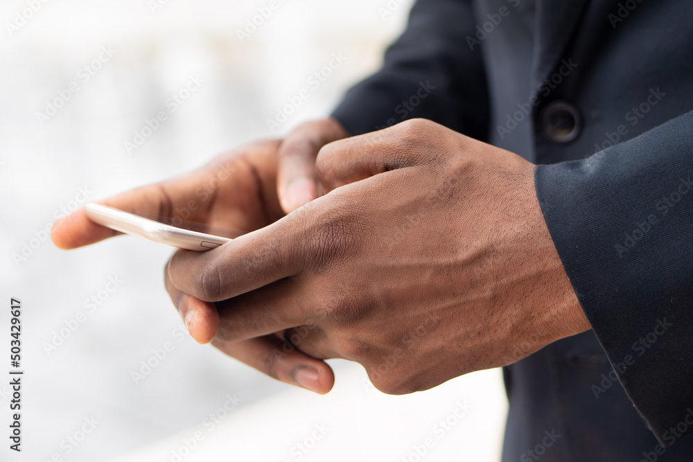 Fototapeta premium Hand of African business man using smartphone mobile application