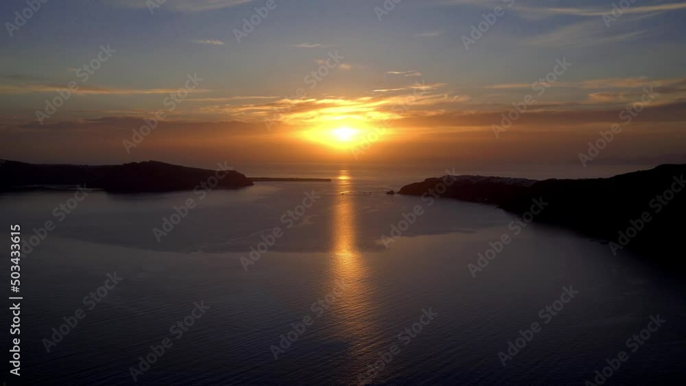 Sun setting in Santorini. Seen from Imerovigli on the Caldera view. Sun shimmers on sea and boats moored to watch sun set. 4k sunset in Greece. Sun setting in Santorini. Seen from Imerovigli on the Caldera view. Sun shimmers on sea and boats moored to watch sun set. 4k sunset in Greece.