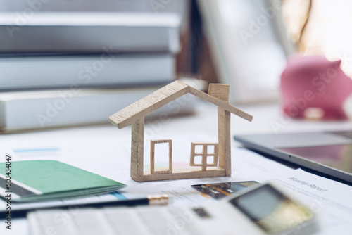 Mockup credit card ,House model, saving account passbook and Notebook on white desk. The concept of buying and paying rent for housing.