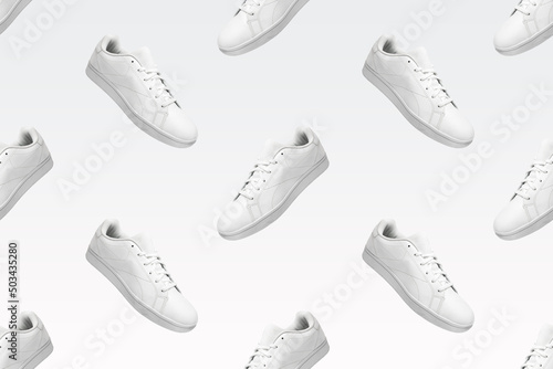 Pattern of white sneakers isolated on white background. Sportive pair of shoes for mockup. Fashionable stylish sports casual shoes. Modern and minimalist wallpaper of fashion lifestyle.