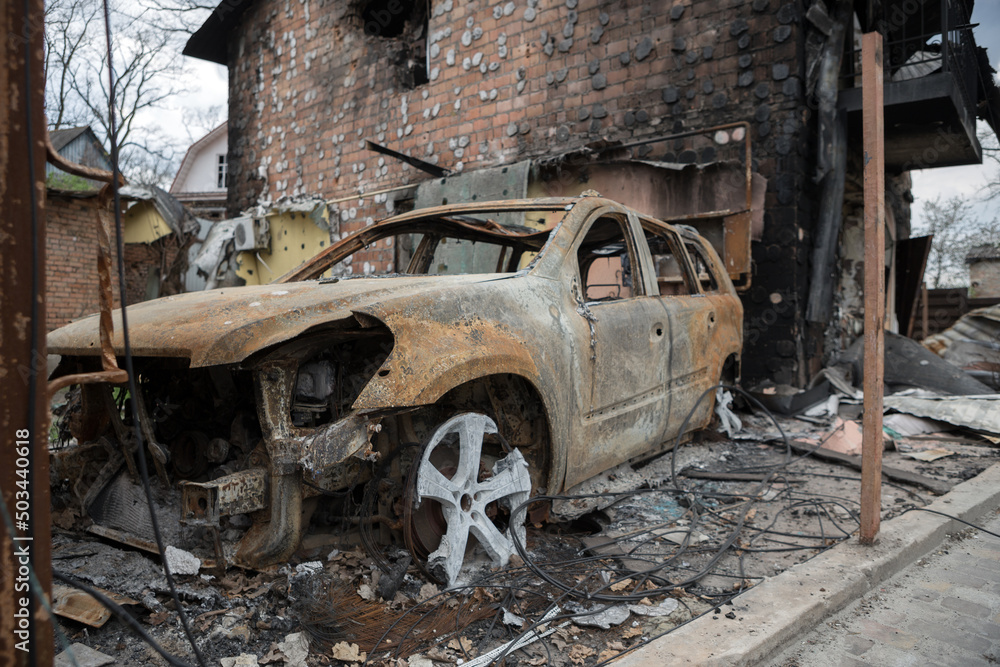 Fototapeta premium War in Ukraine. Ruins of a house and burned car.