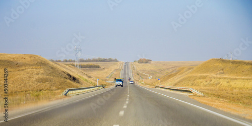 Road and moving cars at daytime and blue sky over