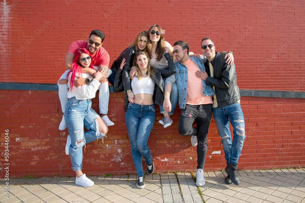 group of seven young friends posing looking at camera outdoor with casual clothes and sunglasses. real people