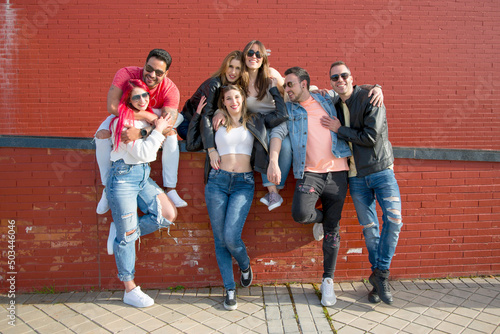 group of seven young friends posing looking at camera outdoor with casual clothes and sunglasses. real people