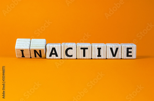 Active or inactive symbol. Turned wooden cubes and changed the concept word Inactive to Active. Beautiful orange table orange background, copy space. Business and active or inactive concept. photo