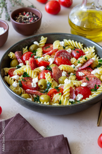 Salad with fusilli pasta, sausage, olives and cottage cheese. Italian food.