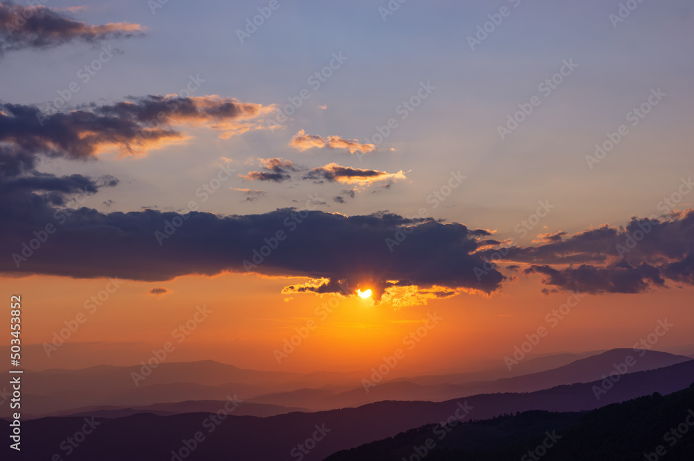 Sunset in the Carpathian mountains. Clouds slightly scatter the harsh sunlight. Warm summer evening