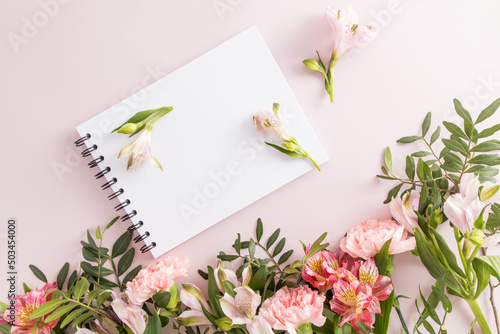 spring composition with flowers and a notebook on a black spring with an empty space for your text. top view. pastel background.