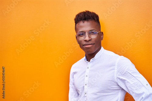 African American businessman in smart shirt and glasses on orange background isolated smiling and looking at the camera. High quality photo