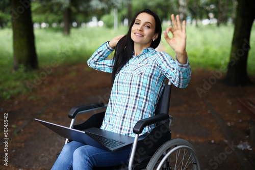 Woman in wheelchair show ok gesture with hand, work during rehabilitation photo