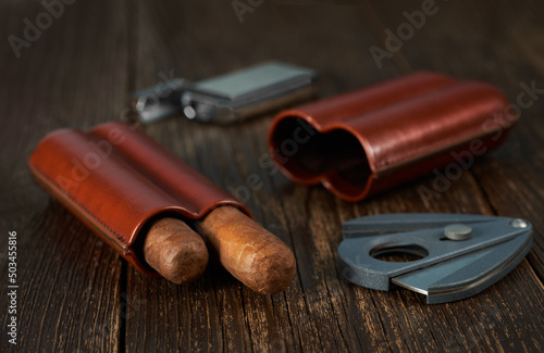 View of a leather case with two Cuban cigars, a lighter and a cutter.